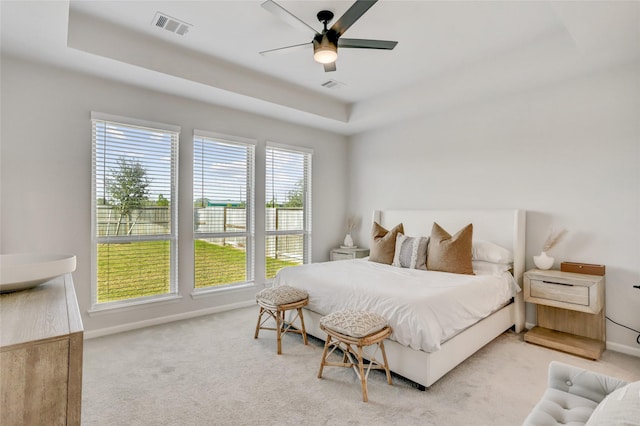 bedroom with ceiling fan, a tray ceiling, and carpet flooring