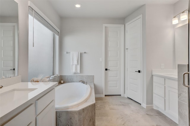 bathroom featuring a relaxing tiled tub and vanity