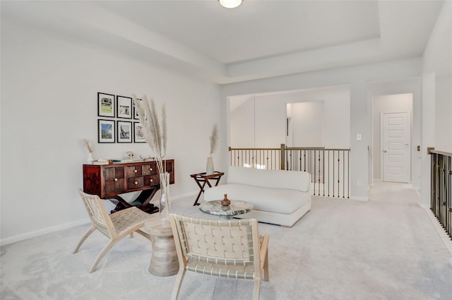 living area featuring a tray ceiling and light carpet