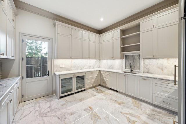 kitchen featuring sink, backsplash, light stone countertops, and white cabinets