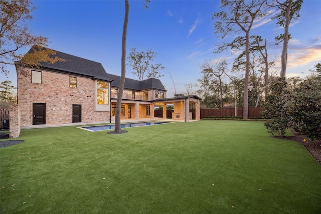 back house at dusk with a fenced in pool, a yard, and a patio area