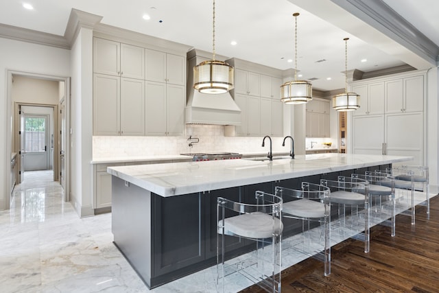 kitchen with hanging light fixtures, light stone countertops, and a large island with sink