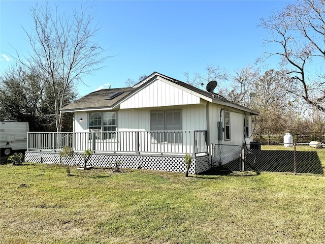 back of property featuring a deck and a lawn