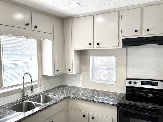 kitchen featuring dark stone countertops, white cabinets, electric range, and sink