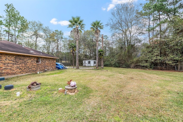 view of yard with an outdoor fire pit and a storage unit