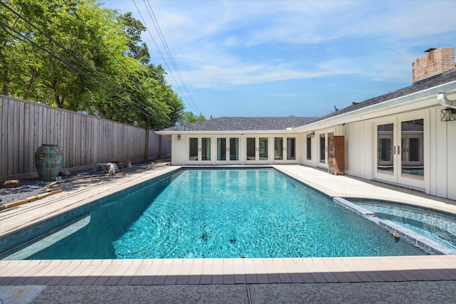 view of pool with french doors, a fenced backyard, and a pool with connected hot tub