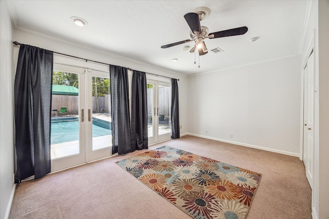 carpeted spare room with ceiling fan, crown molding, and french doors