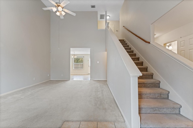 staircase featuring ceiling fan, carpet, and a high ceiling