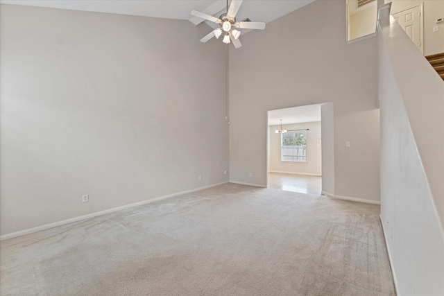 unfurnished living room with light carpet, ceiling fan, and high vaulted ceiling