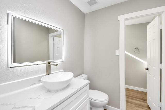 bathroom with hardwood / wood-style floors, toilet, and vanity