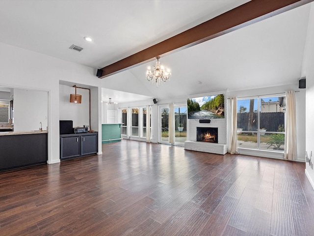 unfurnished living room with a fireplace, dark hardwood / wood-style floors, lofted ceiling with beams, sink, and an inviting chandelier