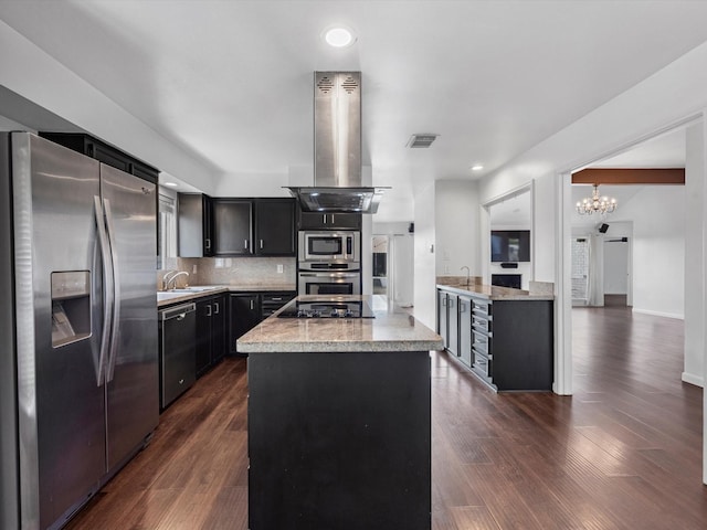 kitchen with island range hood, appliances with stainless steel finishes, decorative backsplash, dark hardwood / wood-style floors, and a kitchen island