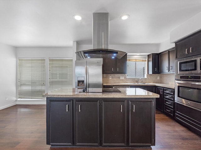 kitchen featuring island range hood, appliances with stainless steel finishes, decorative backsplash, a center island, and sink