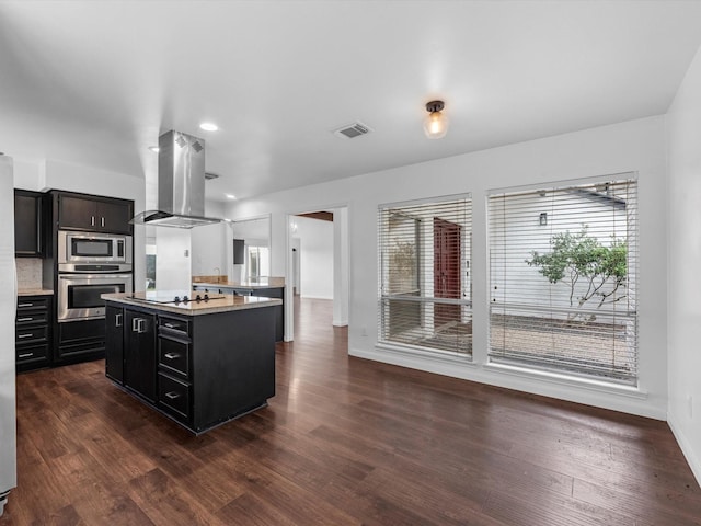 kitchen featuring dark wood-type flooring, appliances with stainless steel finishes, a center island, and island range hood