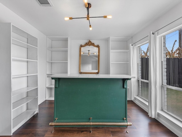 walk in closet with dark wood-type flooring and an inviting chandelier