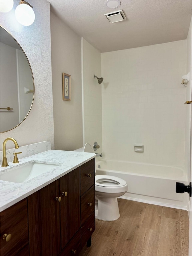 full bathroom with toilet, vanity, wood-type flooring, a textured ceiling, and bathing tub / shower combination