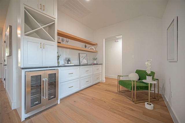 bar with white cabinetry, light hardwood / wood-style floors, and beverage cooler