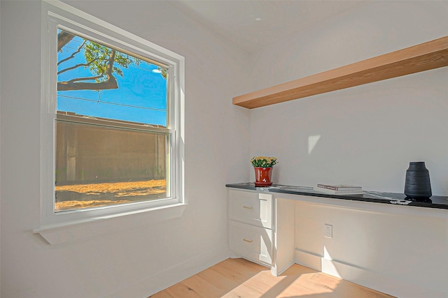 unfurnished office featuring built in desk and light wood-type flooring