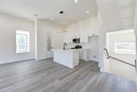 kitchen with white cabinetry, a center island with sink, and hardwood / wood-style floors