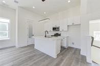 kitchen featuring light hardwood / wood-style floors, white cabinets, and an island with sink