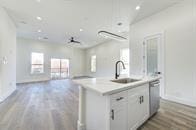 kitchen featuring sink, white cabinetry, a center island with sink, and a healthy amount of sunlight