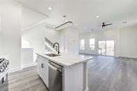 kitchen with stainless steel dishwasher, stove, sink, white cabinetry, and a kitchen island with sink