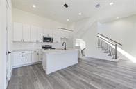 kitchen featuring dark hardwood / wood-style floors, white cabinetry, and a center island with sink