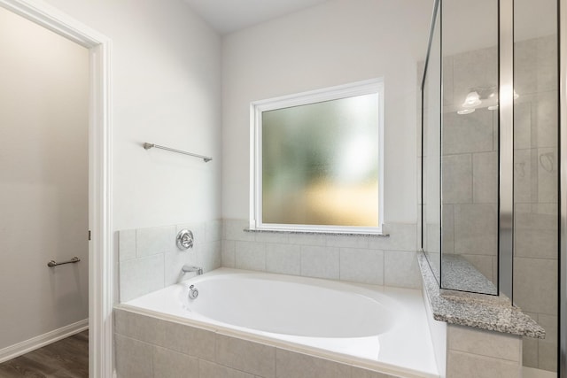 bathroom with tiled bath and hardwood / wood-style floors