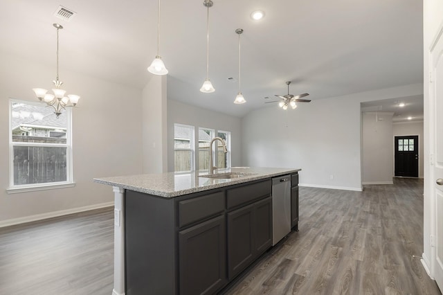 kitchen with dishwasher, a center island with sink, sink, light stone counters, and ceiling fan with notable chandelier