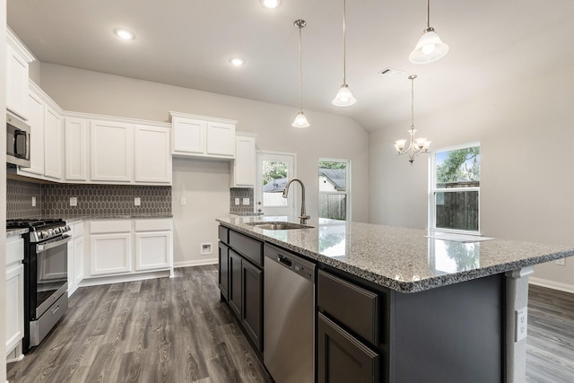 kitchen with pendant lighting, white cabinets, stainless steel appliances, sink, and a center island with sink