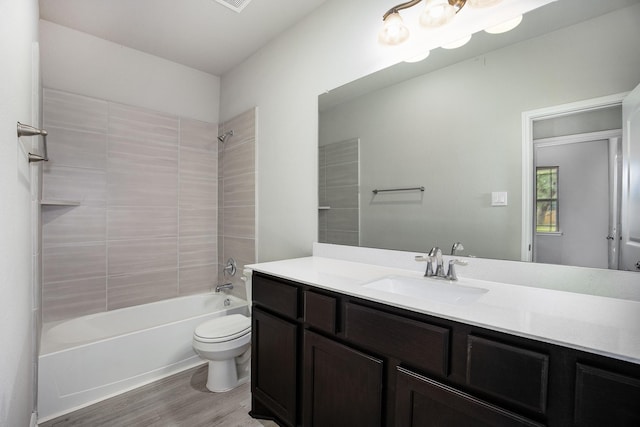 full bathroom with toilet, tiled shower / bath, hardwood / wood-style floors, and vanity