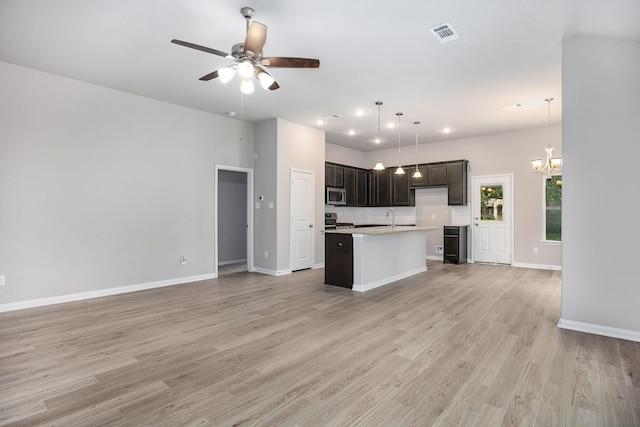 kitchen featuring decorative light fixtures, light hardwood / wood-style floors, appliances with stainless steel finishes, an island with sink, and ceiling fan with notable chandelier