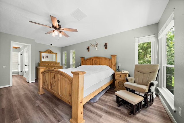 bedroom featuring ceiling fan, multiple windows, and dark hardwood / wood-style floors