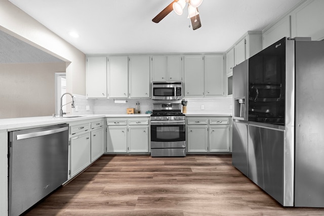 kitchen featuring ceiling fan, backsplash, sink, hardwood / wood-style flooring, and stainless steel appliances