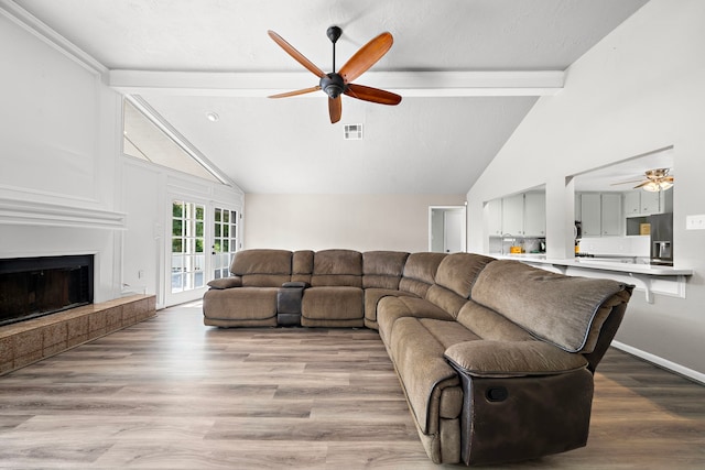 living room with ceiling fan, vaulted ceiling with beams, and light wood-type flooring