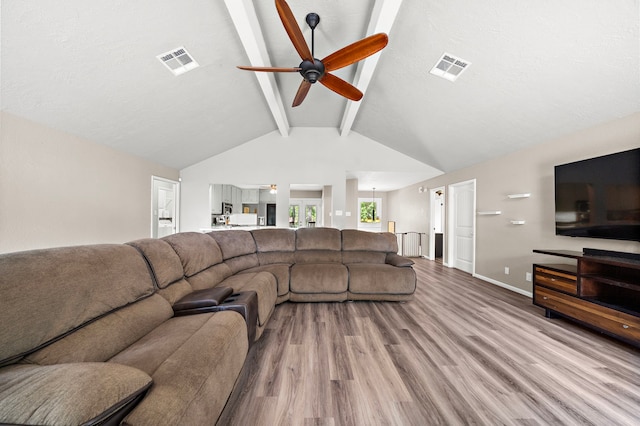 living room featuring ceiling fan, light hardwood / wood-style floors, a textured ceiling, and lofted ceiling with beams