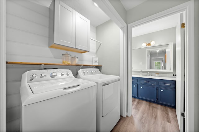 washroom with washer and clothes dryer, light wood-type flooring, sink, and cabinets