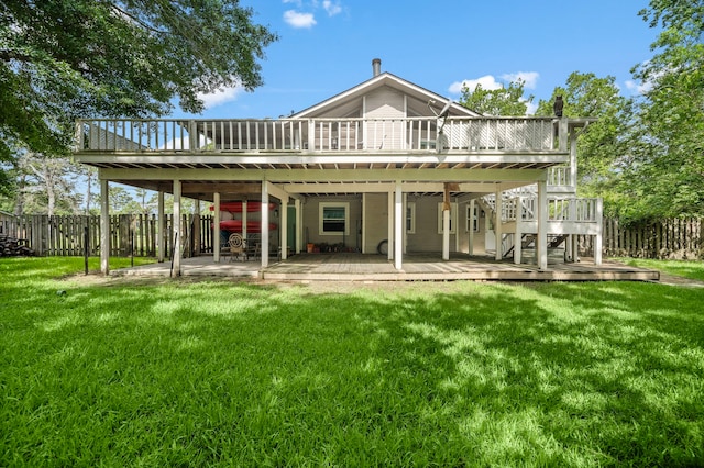 back of property featuring a deck, a patio area, and a lawn