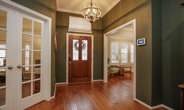 foyer entrance with hardwood / wood-style flooring, an inviting chandelier, ornamental molding, and french doors