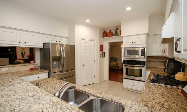 kitchen featuring light stone counters, white cabinets, appliances with stainless steel finishes, and crown molding