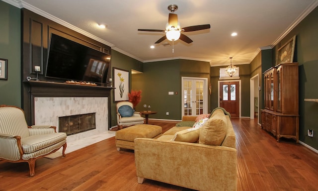 living room with ceiling fan with notable chandelier, wood-type flooring, ornamental molding, and french doors