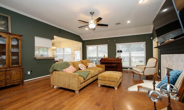 living room featuring ceiling fan, lofted ceiling, a fireplace, hardwood / wood-style floors, and crown molding