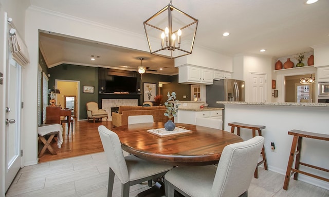 dining room with ceiling fan with notable chandelier and ornamental molding