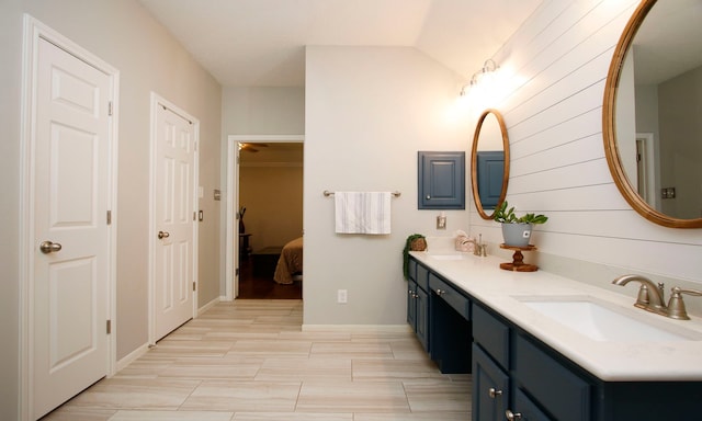 bathroom with ceiling fan, vanity, wood walls, and vaulted ceiling