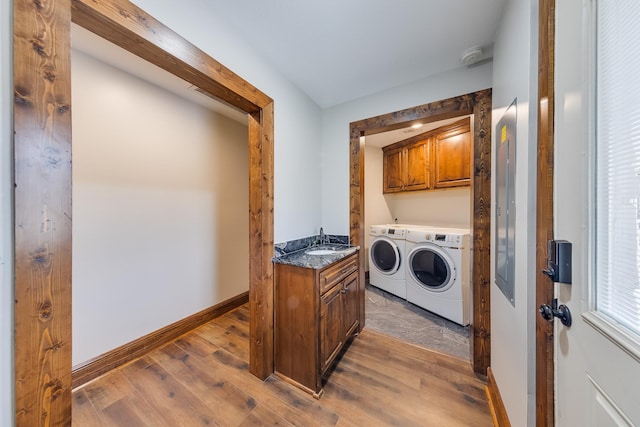 laundry area featuring cabinets, washer and dryer, wood-type flooring, and sink