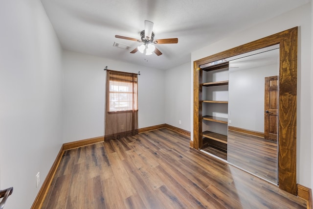 unfurnished bedroom with ceiling fan, dark wood-type flooring, and a closet