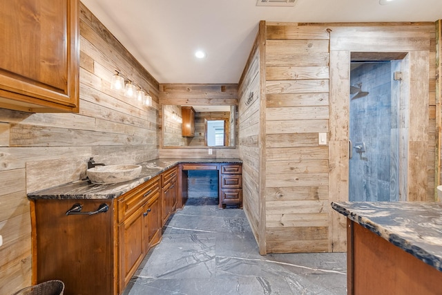 bar with sink, dark stone counters, and wooden walls