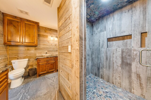 bathroom featuring toilet, vanity, a shower, and wood walls