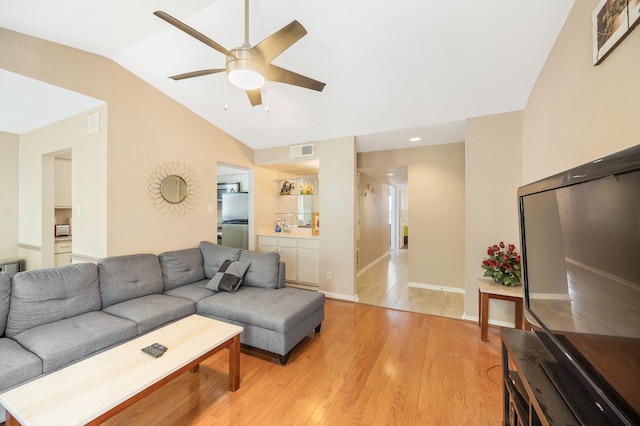 living room featuring ceiling fan, lofted ceiling, and light wood-type flooring