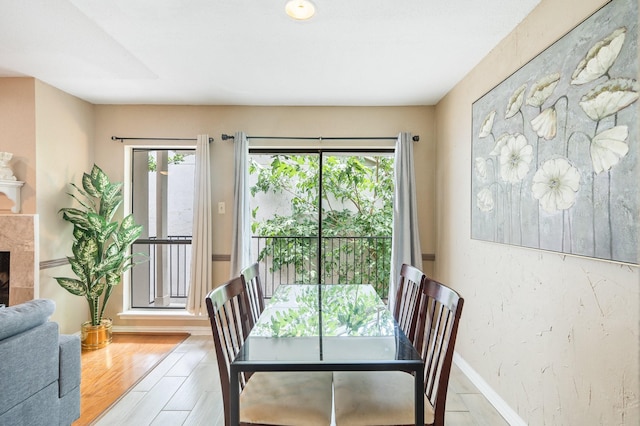 dining area with a high end fireplace, plenty of natural light, and light hardwood / wood-style floors